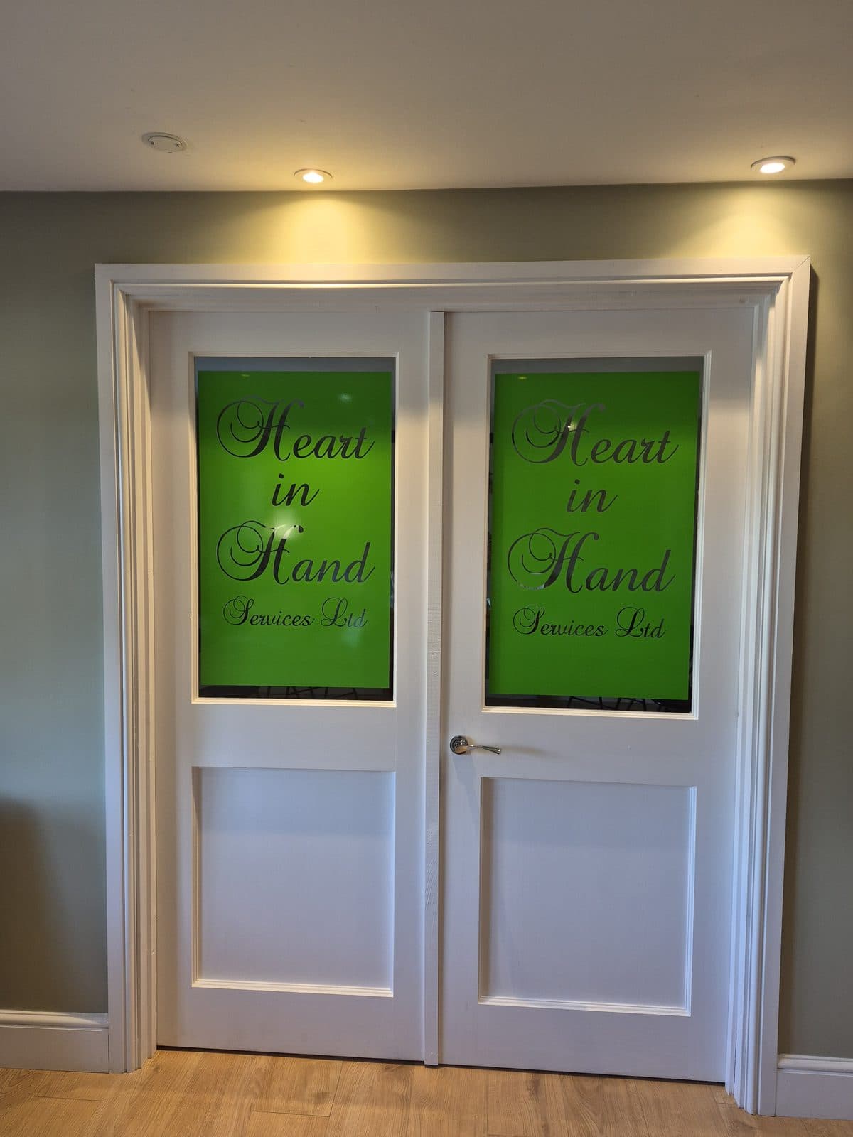 White double doors with the Heart in Hand Services Ltd logo set in the glass panels